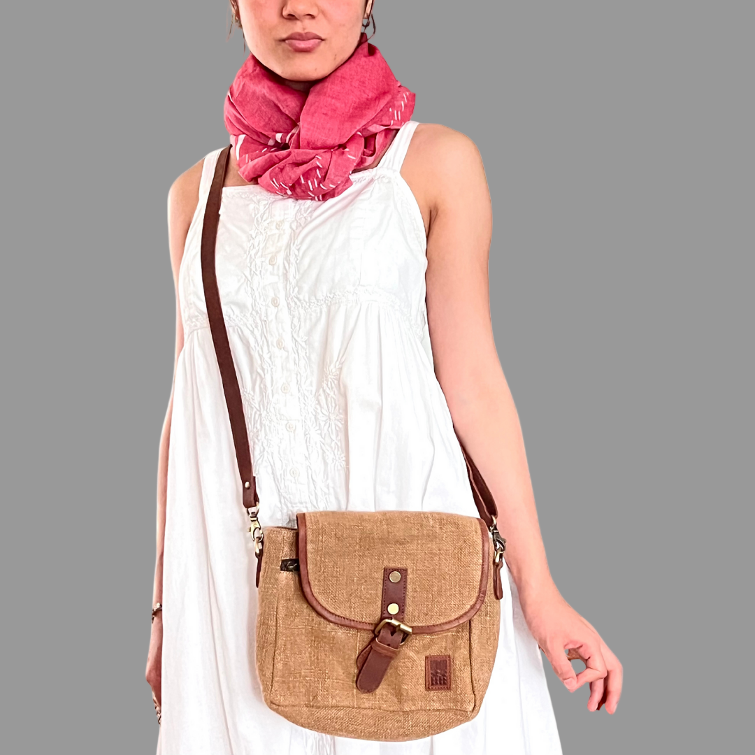 Woman wearing a camel crossbody bag and a pink cotton scarf qith white striped and diamond Jamdani patterns