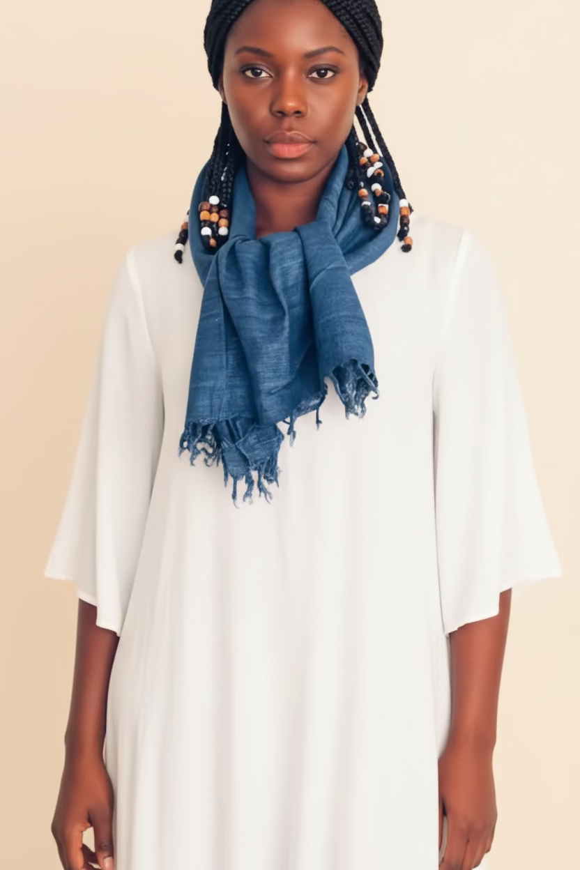 Person wearing a blue scarf and earrings on a beige background
