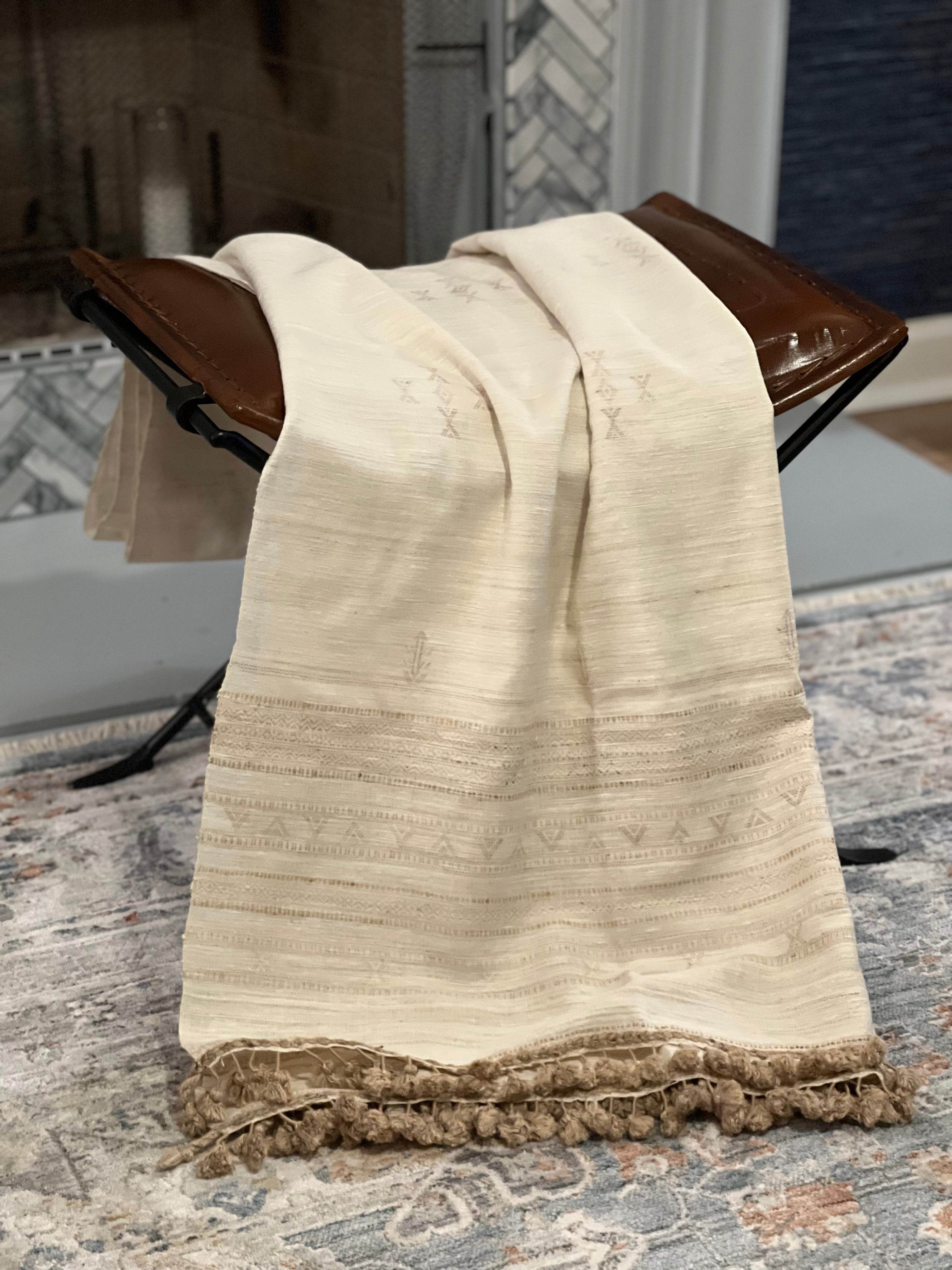Beige Fine Silk-Wool textured throw blanket draped over a wooden stool.