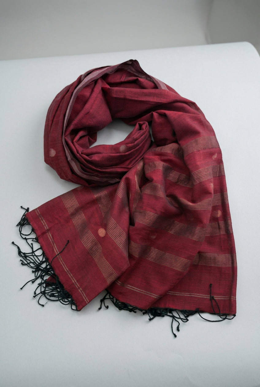 A folded and draped red scarf with black fringe tassels and subtle beige stripes, shown on a plain white background.