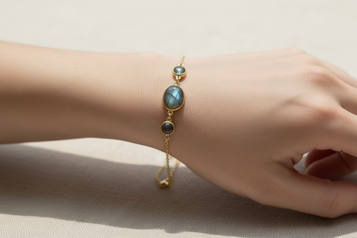 Gold bracelet with green gemstones on a wrist against a neutral background