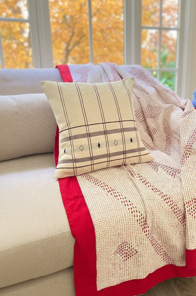 Decorative pillow on a couch with a kantha stitched throw blanket