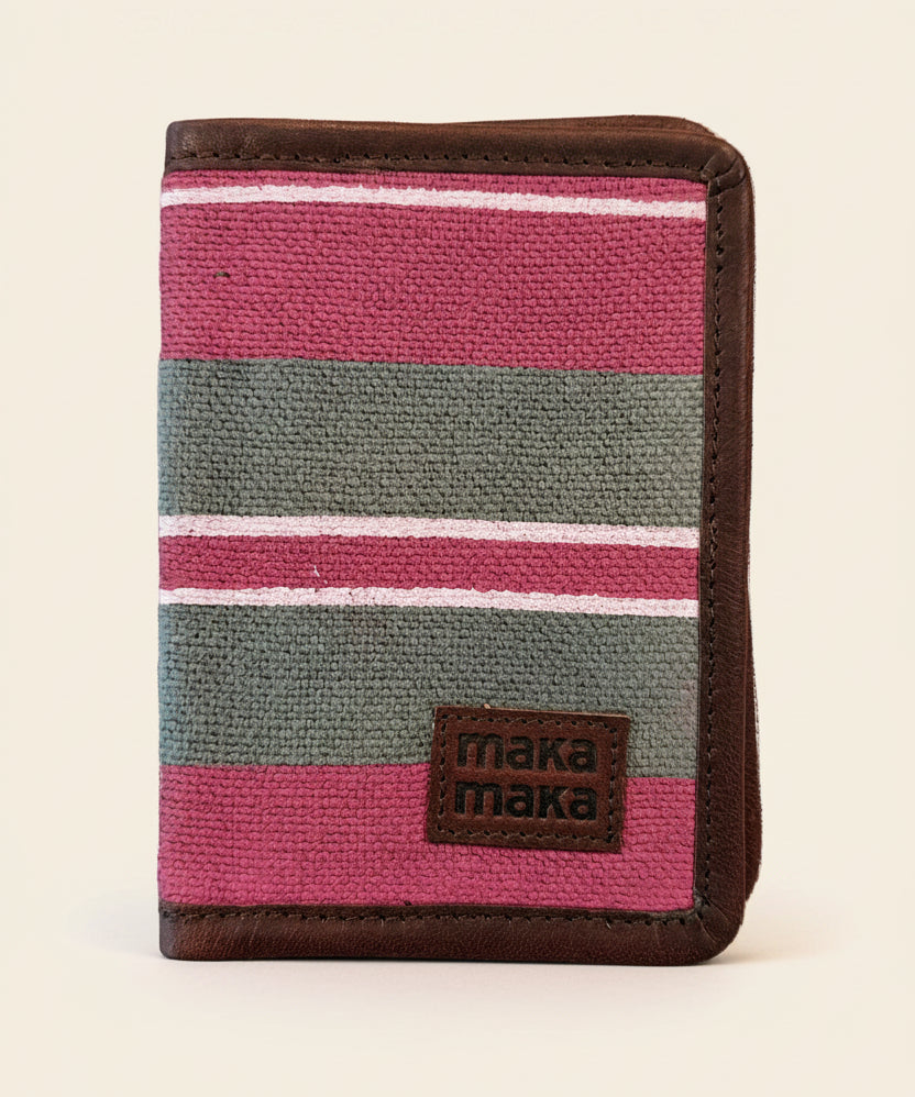 Pink and grey stripe block printed burlap-canvas passport holder with leather trim -_closed with dark brown leather trim and a 'maka maka' logo. 