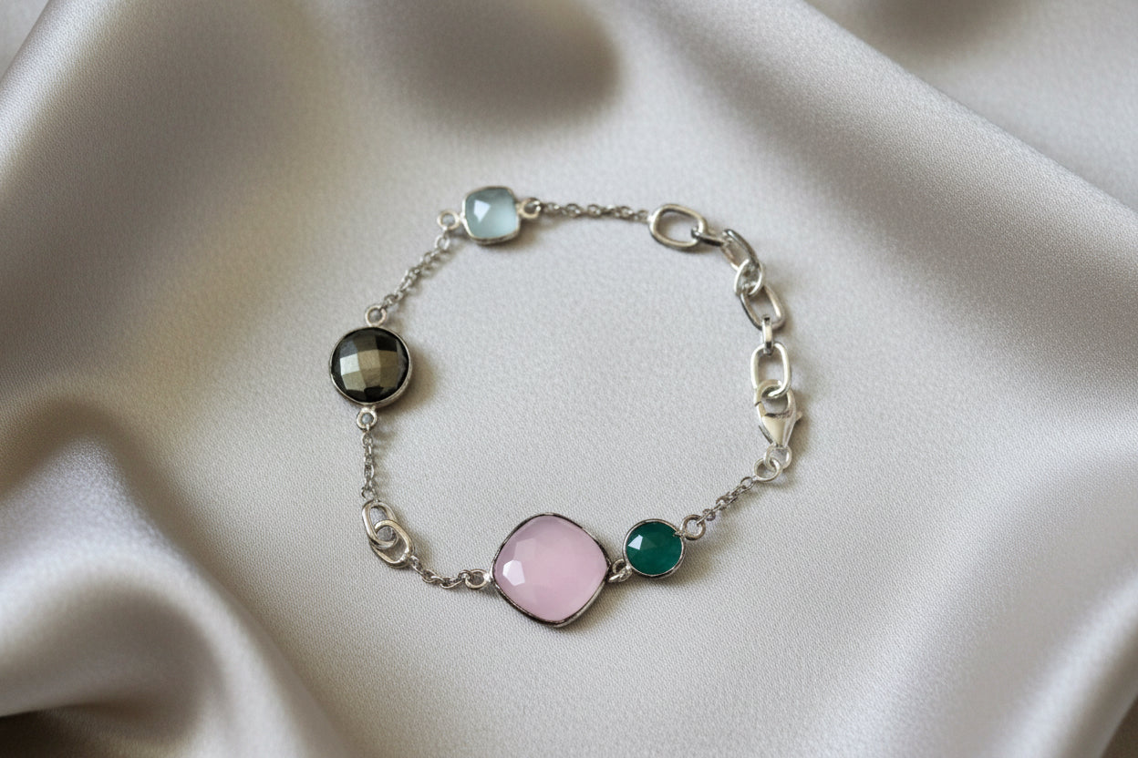 Silver bracelet with colorful gemstones on a beige fabric background